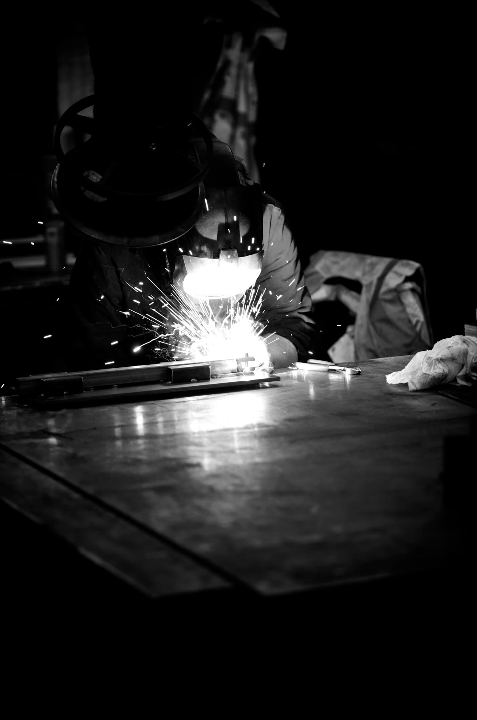 Skilled technician welding hydraulic components in the workshop with sparks flying