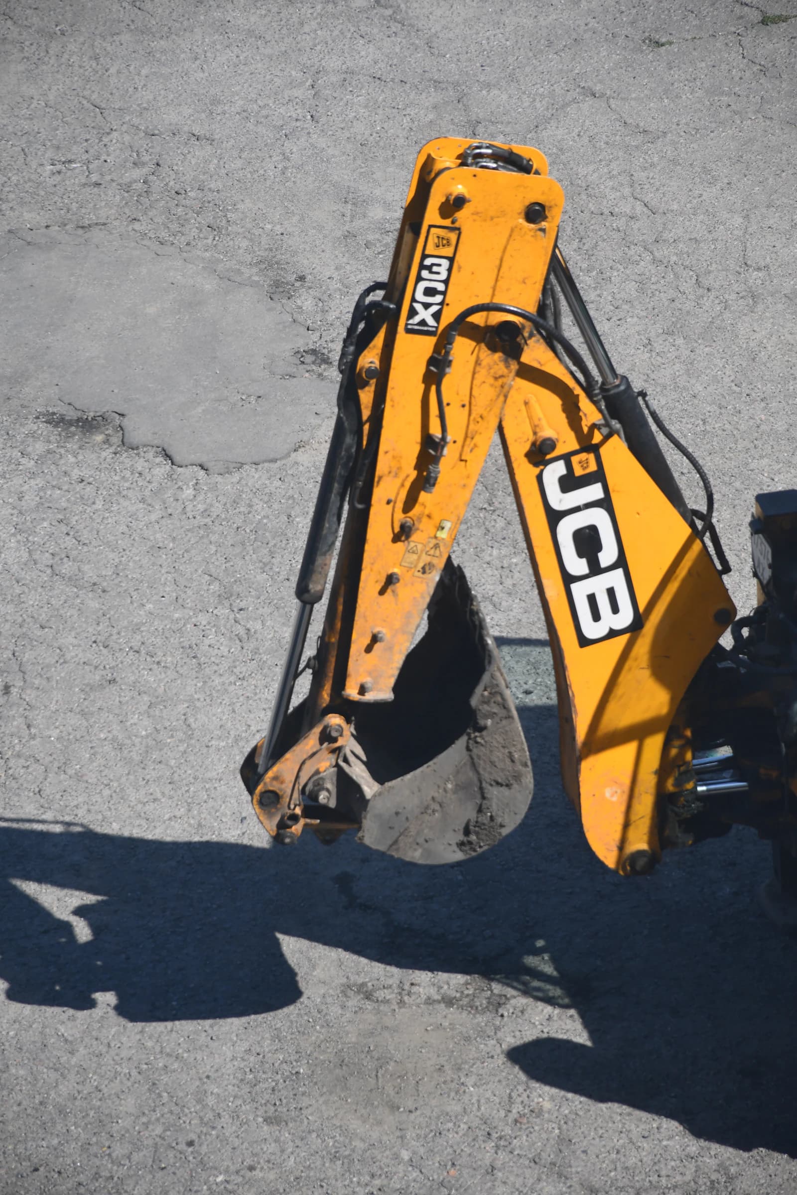 Yellow excavator arm and bucket ready for hydraulic service at a heavy equipment yard